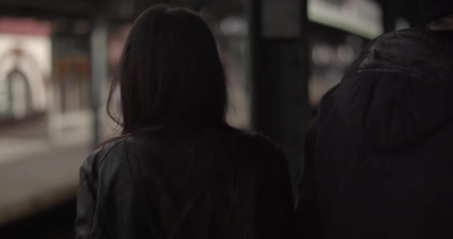 A man and woman walking on a train platform