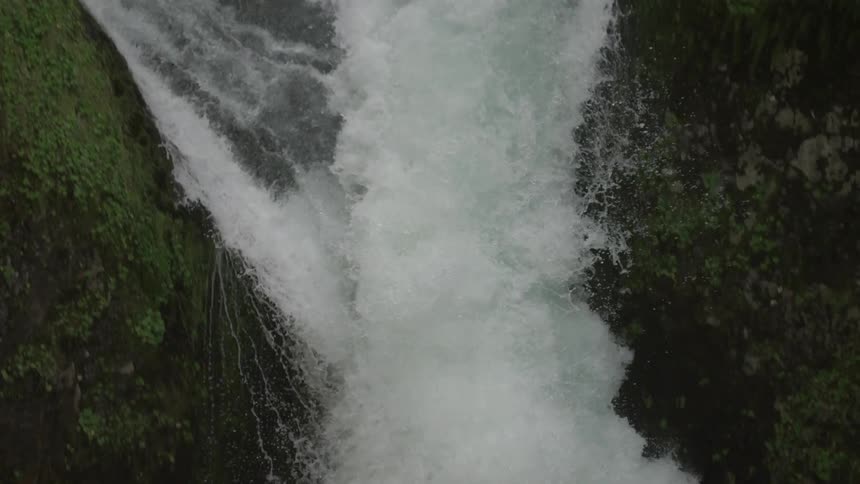 The camera slowly pans right and follows Punchbowl Falls to the pool below in the Columbia River Gorge along Eagle Creek