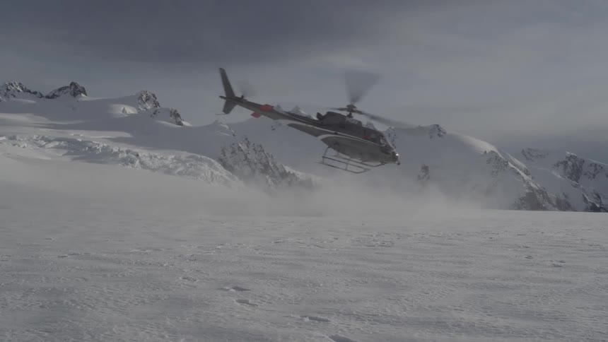 A helicopter flies in the snowy mountains