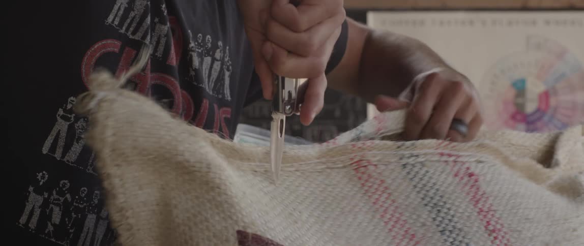 Man cuts open a cloth bag with a knife