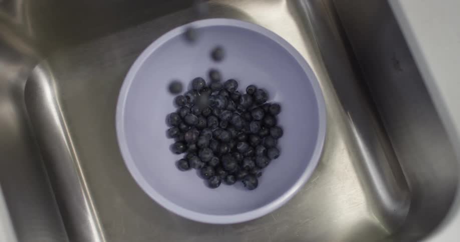 Blueberries fall into a bowl