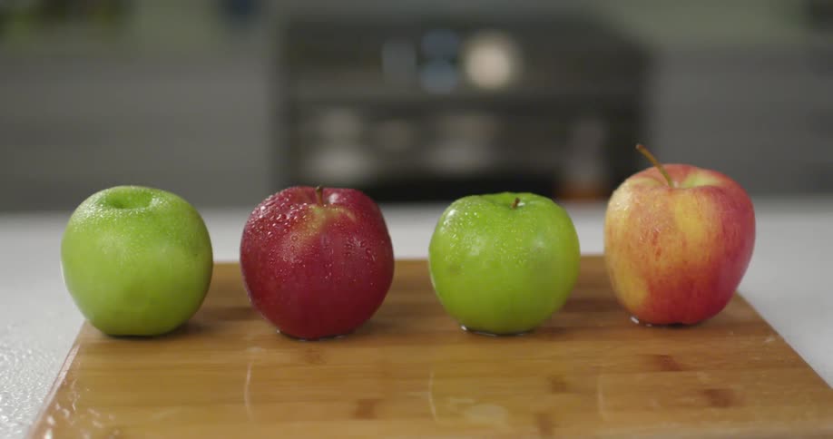 Two red and two green apples on cutting board