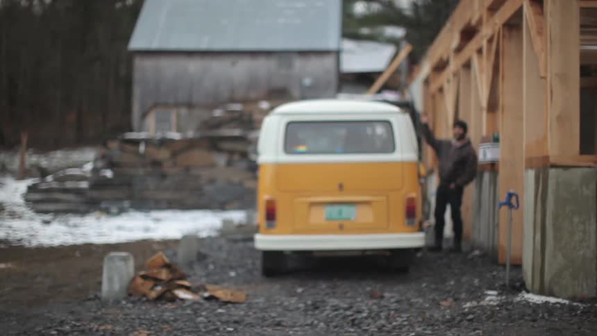 A man stands by a van and waves