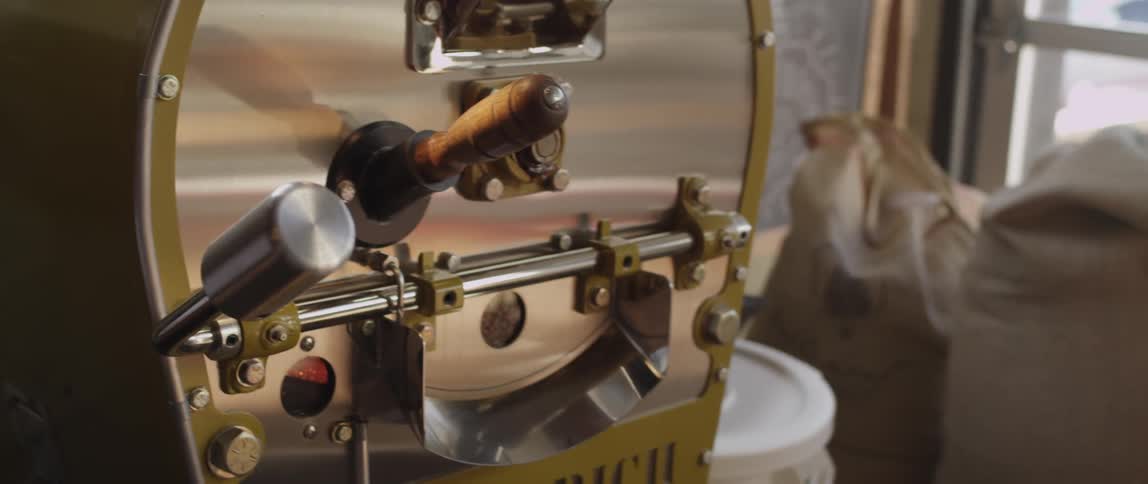 A person inserts a spade type tool filled with something into a larger machine