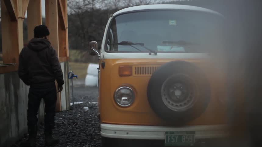 A man stands beside an orange vw van