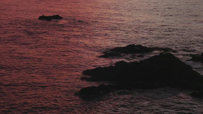 Water ripples around a large rock in the sea
