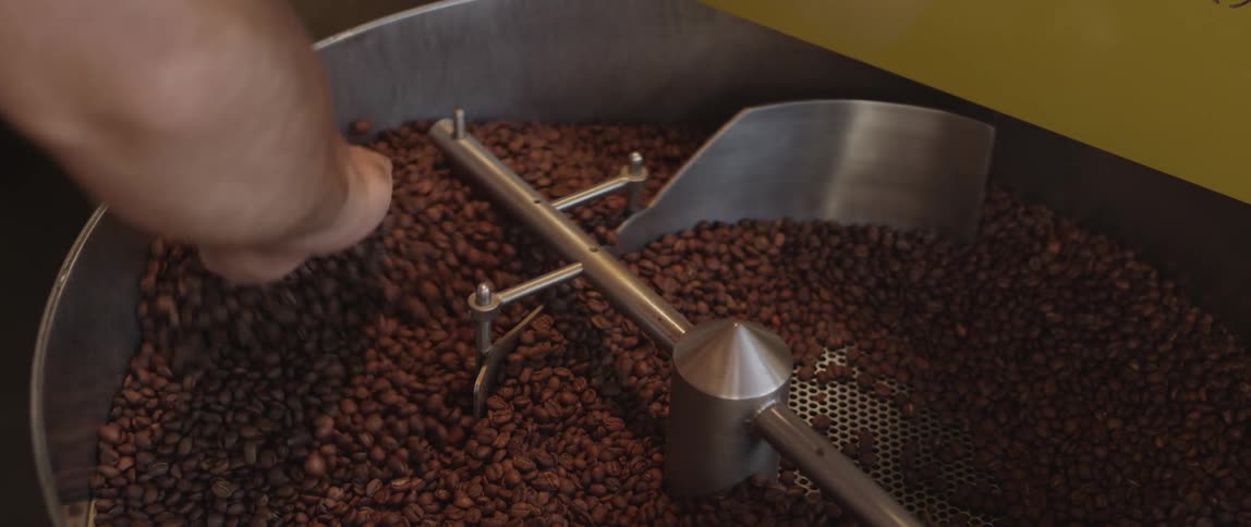 Man and machine mix coffee beans