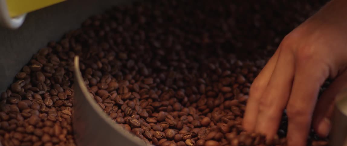 A person running their hand thru coffee grounds