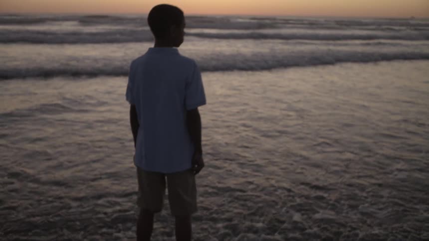 Waves roll over a boy's feet