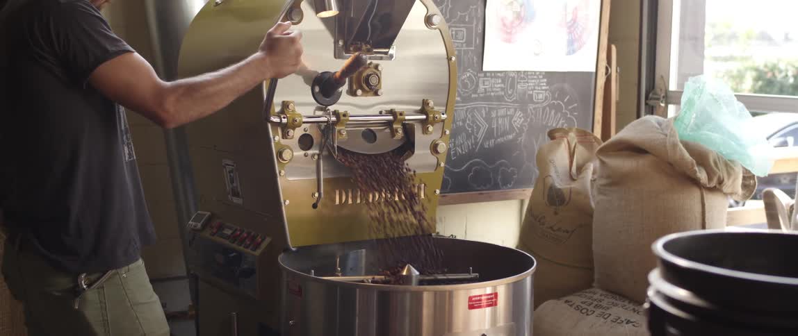 A man operates a coffee bean roasting machine