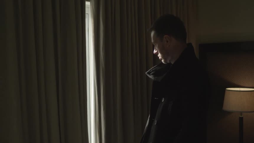 A man stands looking out a window