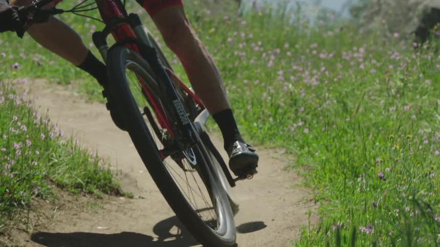 Man bikes down a small grassy trail