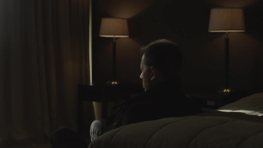 Man on hotel room floor against bed