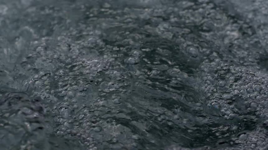 Abstract shot of water swirling and churning alongside the bank of the river, the water is extremely clear and clean