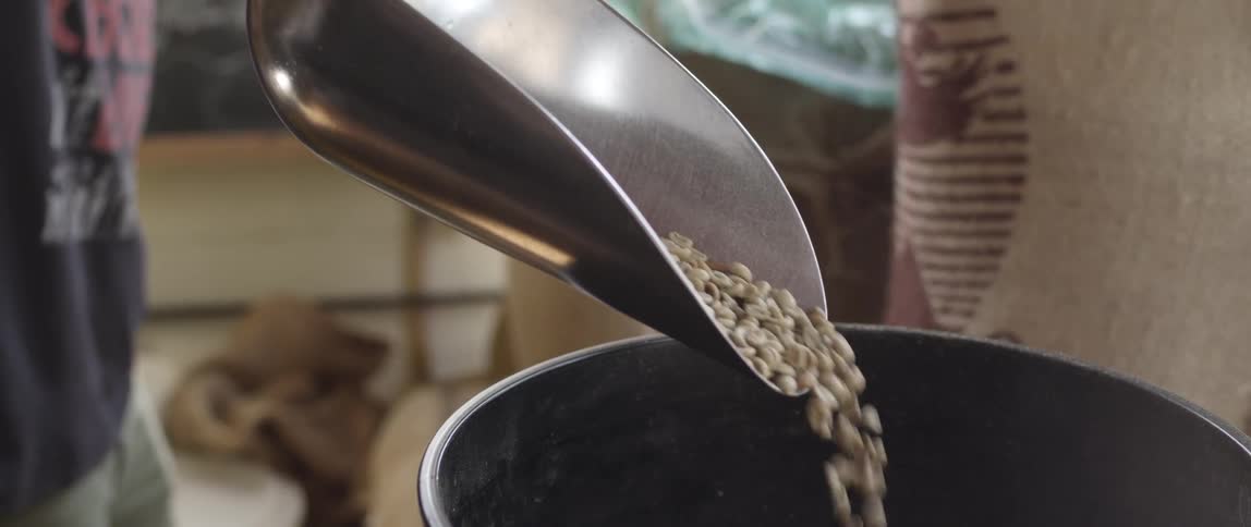A man scoops coffee beans from a bin