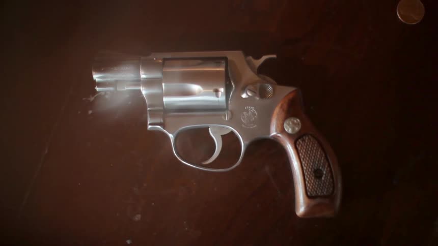 A small silver revolver with a wooden handle