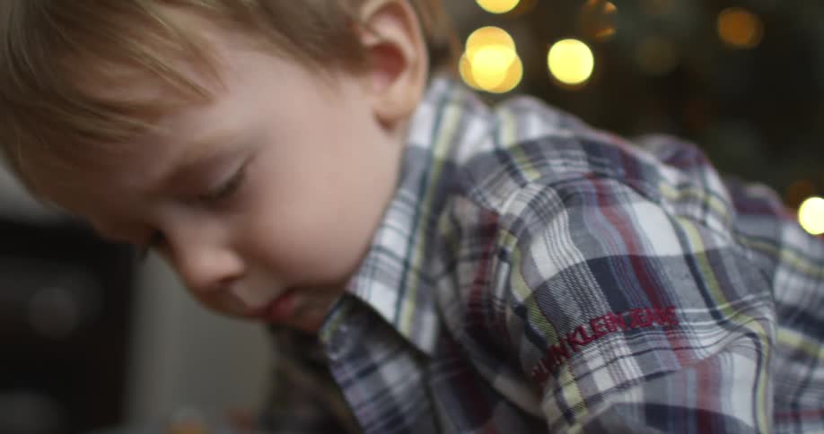 A boy sits in front of an illuminated christmas tree