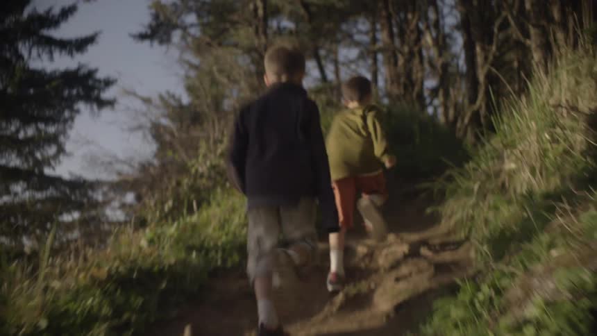 Boys run up trail into trees