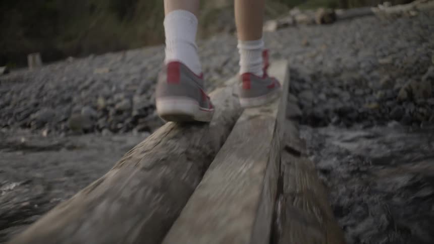 A person is walking along some wooden planks over water