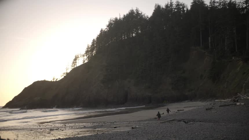 Children run along the beach at sunset