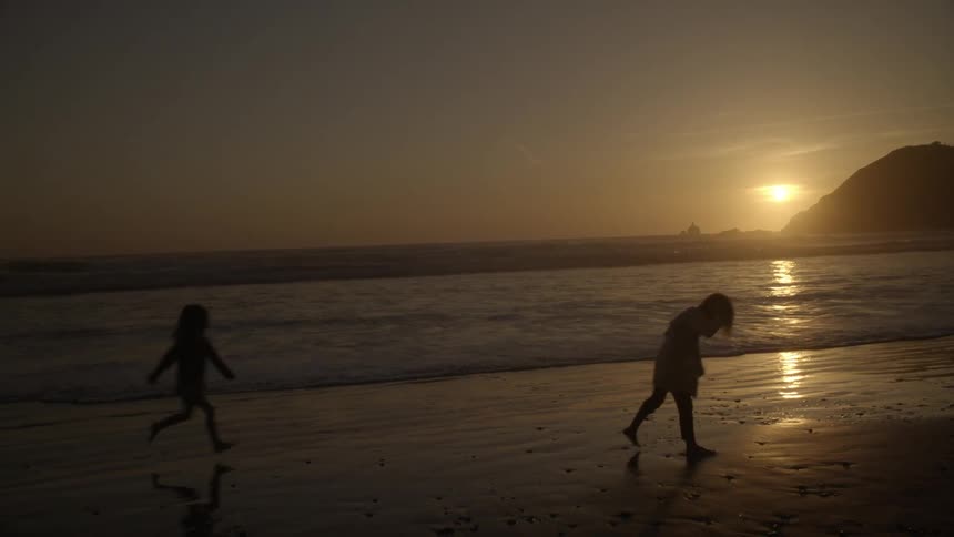 Children playing on beach at sunset