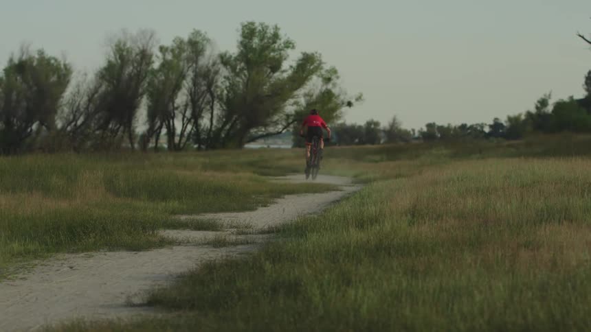 A cyclist riding his bicycle across open grasslands