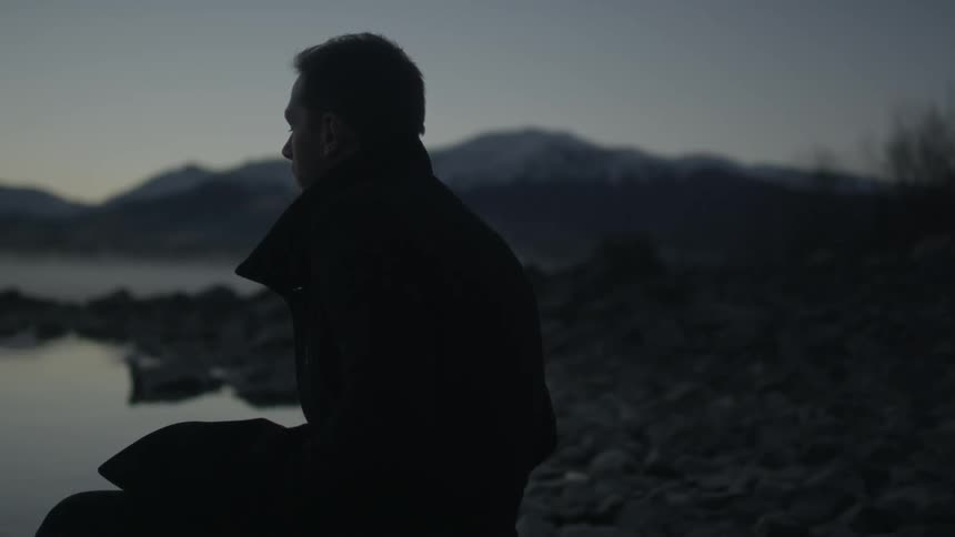 A person sitting down looking at a lake