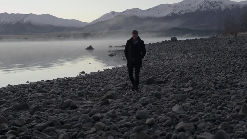 A man walks on a rocky beach