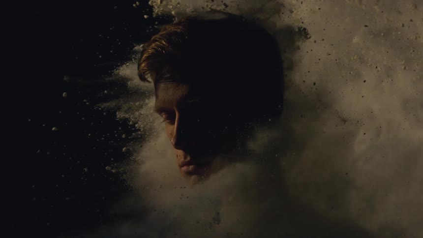 Man's head getting hit from behind by a cloud of white sand or powder