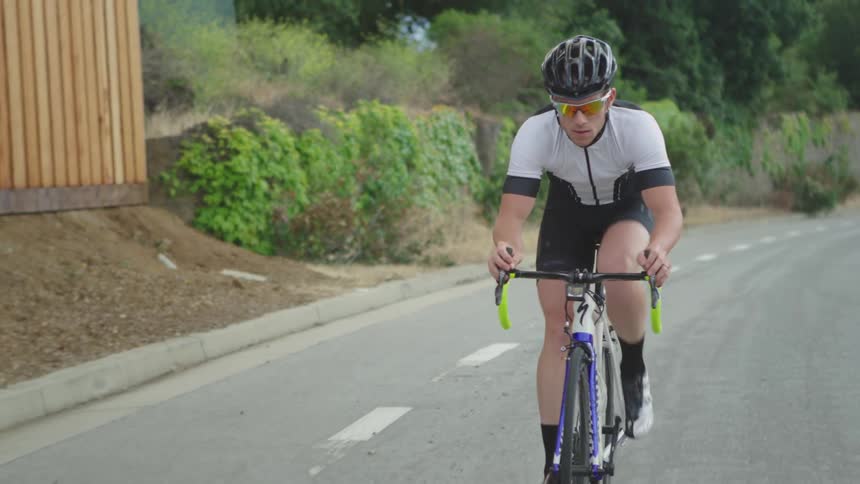 A man bicycles down a road