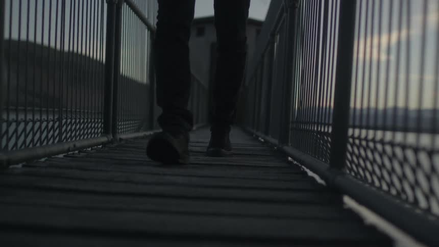 A man walks across a foot bridge