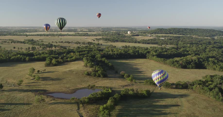 Hot air balloons floating over a field and a pond