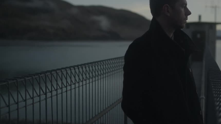 A man standing on a bridge and lost in thoughts