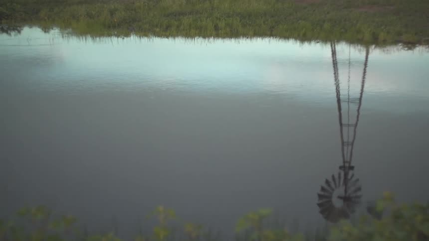 A windmill in the reflection of a pond