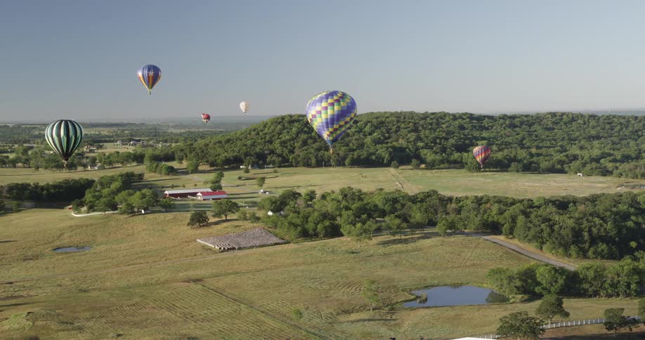 Hot air balloons floating over farmland