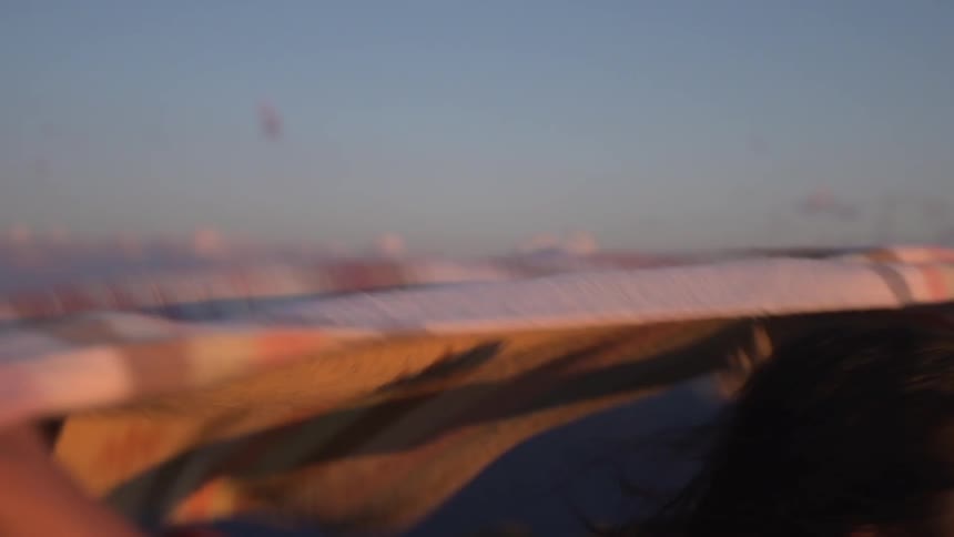 A woman holding a scarf over her head and letting the wind whip the scarf behind her
