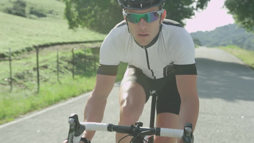Man in black and white bikes down a road