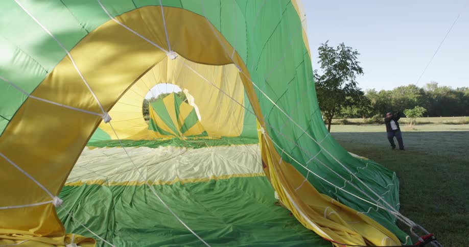 Man pulling on the rope of a large hot air balloon