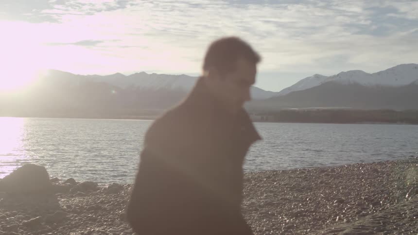 Man walks along rocky shore