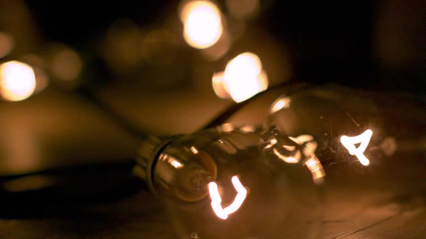 A lit lightbulb laying on its side while other lights glow in the background