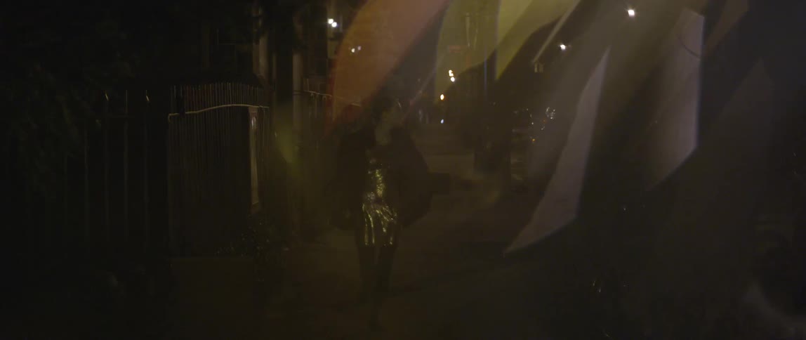 A person walking down a sidewalk at night