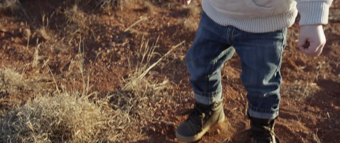 A boy picking up dirt then throwing it