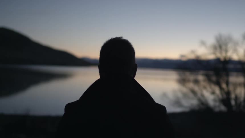 Man walks toward water at sunset