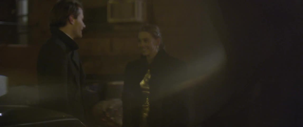 Man smiles as woman in gold dress walks up