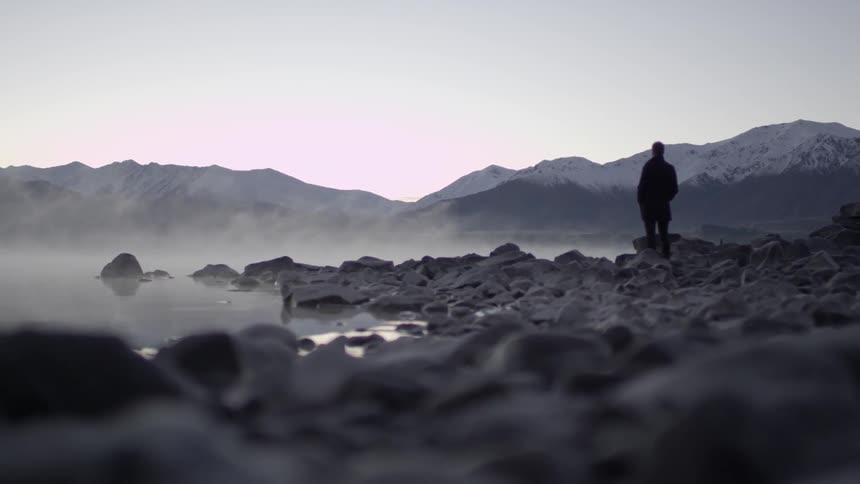 A man stands on a rocky shore