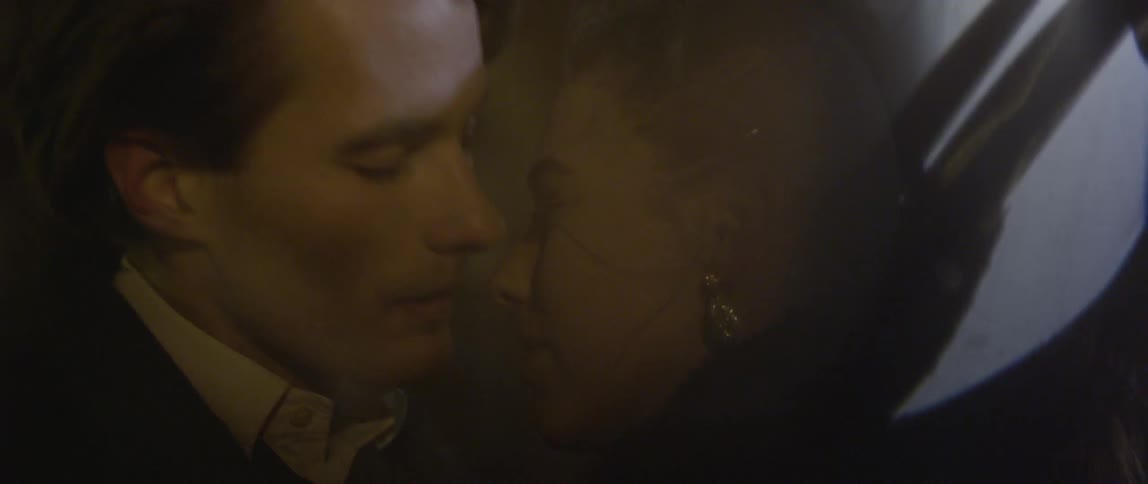 Well dressed man and woman share a kiss