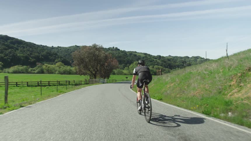 A male cyclist cycles on a countryside road