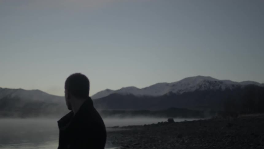 A man watches a mist covered lake