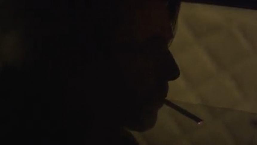 Man smokes his cigarette looking out the window