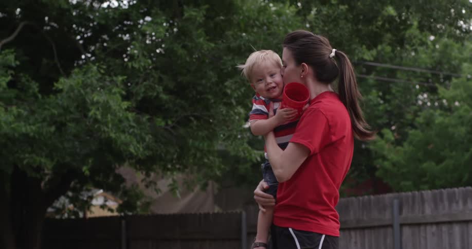 A mother holding and kissing her toddler boy